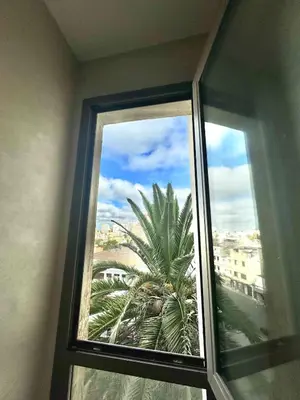a window with a view of a palm tree at Studio Cosy au Centre de Casablanca, Idéal pour Découvrir la Ville in Casablanca-Port