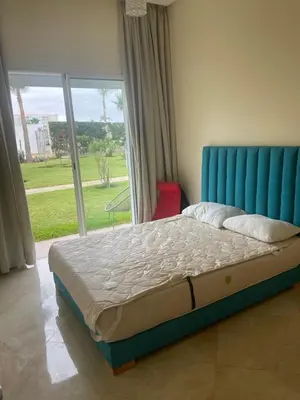 a bed with a blue headboard in a room with a window at Casabay Sidi Rahal, à 2mn de la mer en bord de piscine et jardin in Sidi Rahal