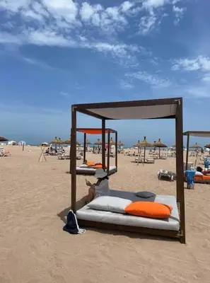a group of beds on a sandy beach at Casabay Sidi Rahal, à 2mn de la mer en bord de piscine et jardin in Sidi Rahal