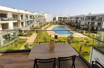 a table on a balcony with a view of a pool at résidence à louer in Nouaceur