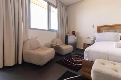 a bedroom with a bed and two chairs and a window at Studio prestige avec Terrasse sur la Marina in Casablanca