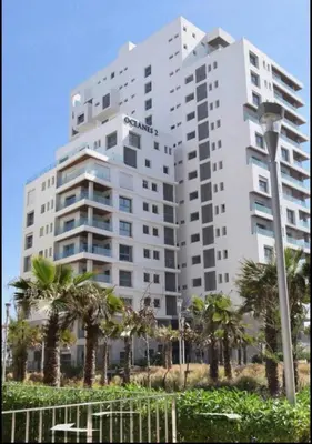 a large white building with palm trees in front of it at Studio prestige avec Terrasse sur la Marina in Casablanca