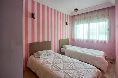 two beds in a room with pink and white stripes at Appartement de luxe Résidence Du Palais GHANDI in Casablanca