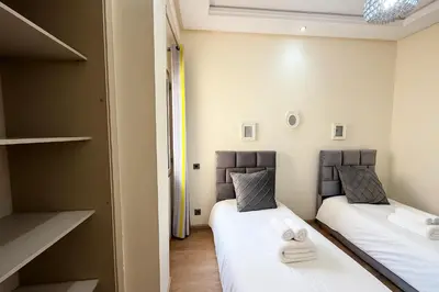 two beds in a small room with white sheets at Cosy ensoleillé 2CH proche de Mosquee hassan II et corniche in Casablanca