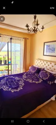 a bedroom with a large purple bed with a window at Mansouria beach resort in Mohammedia