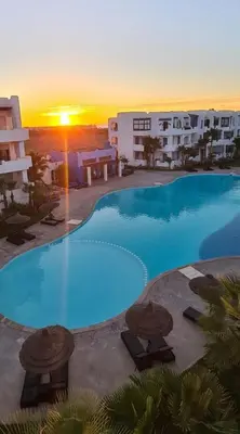 a large swimming pool with a sunset in the background at Mansouria beach resort in Mohammedia