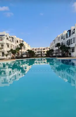 a swimming pool in front of some apartment buildings at Mansouria beach resort in Mohammedia