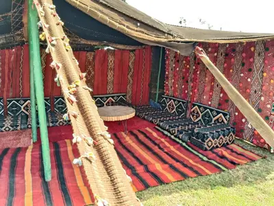 a hammock with a couch and a table in a tent at Ferme