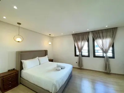 a bedroom with a large bed and two windows at 2br near TGV station in Rabat