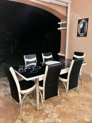 a table with four chairs and a black table at Appartement du luxe au cœur du Golf in Bouznika