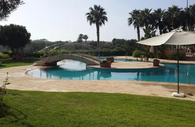 a large swimming pool with a bridge in a park at Appartement du luxe au cœur du Golf in Bouznika