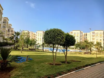 a park with trees and buildings in a city at appartement 75m2 avec piscine in Bouznika