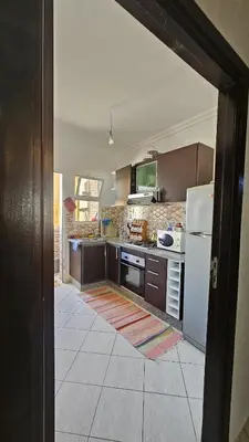a kitchen with brown cabinets and a white refrigerator at appartement 75m2 avec piscine in Bouznika