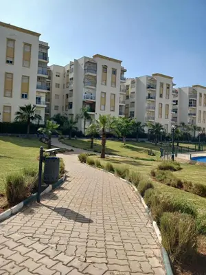a brick walkway in a park in front of apartment buildings at appartement 75m2 avec piscine in Bouznika
