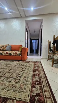 a living room with an orange couch and a rug at appartement 75m2 avec piscine in Bouznika