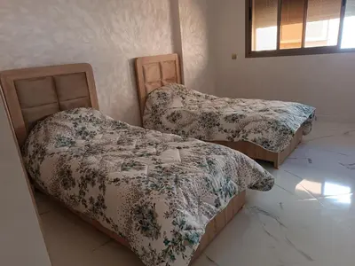 two beds sitting in a room with a unintention at Jolie appartement Bouznika in Bouznika