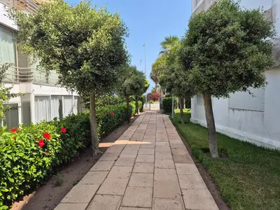 a sidewalk with trees and flowers next to a building at Résidence balnéaire Les perles de Tamaris in Tamaris