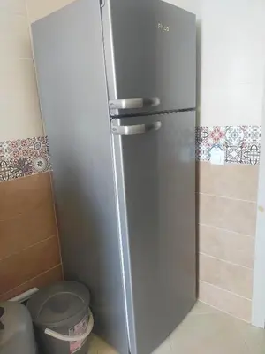 a stainless steel refrigerator in a kitchen with a trash can at Appartement calme et confortable in Bouznika