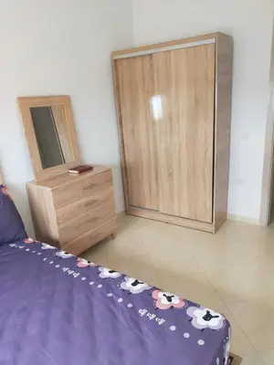 a bedroom with a bed and a wooden dresser at Appartement calme et confortable in Bouznika