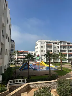 a pool in a park with palm trees and buildings at Studio bord de mer , La Siesta Beach Resort in Mohammedia