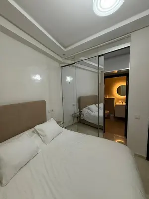 a bedroom with a large white bed and a mirror at Elegant apartment Racine Bd AlMassira in Casablanca