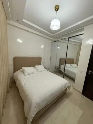 a bedroom with a white bed and a mirror at Elegant apartment Racine Bd AlMassira in Casablanca