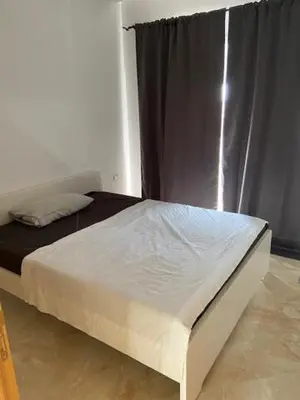 a bed in a room with a curtain and a bed sidx sidx sidx at Appartement Kettani bouznika in Bouznika