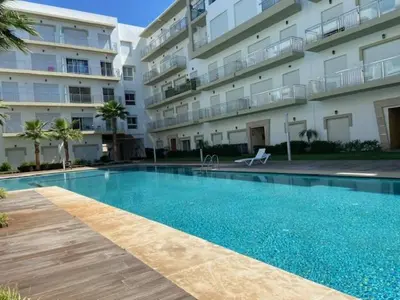 a swimming pool in front of a apartment building at Appartement Kettani bouznika in Bouznika