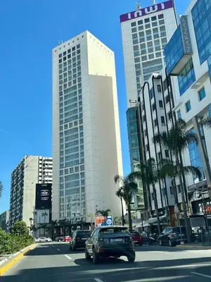 a car driving down a city street with tall buildings at Large bright and centrally located studio in Casablanca