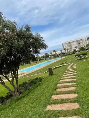 a stone path leading to a pool with a tree at APPART AMIR Belle Appartement avec pecine in Dar Bouazza