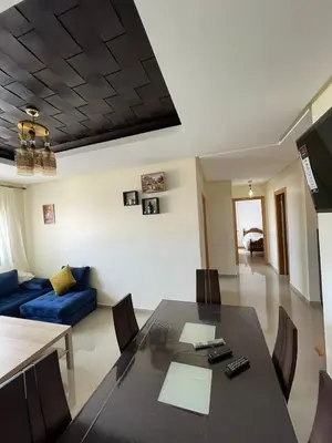 a living room with a table and a blue couch at APPART AMIR Belle Appartement avec pecine in Dar Bouazza
