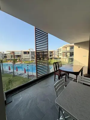 a balcony with a table and chairs and a large window at Sidi Rahal Oceanic Appartement vue sur piscine in Sidi Rahal