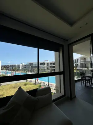 a living room with a couch and a view of the beach at Sidi Rahal Oceanic Appartement vue sur piscine in Sidi Rahal