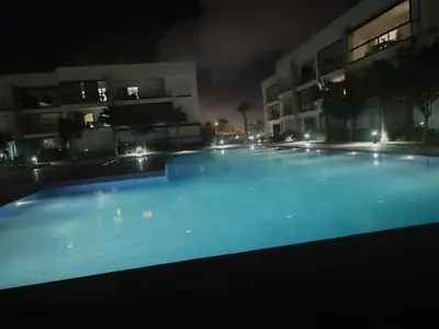a large swimming pool in front of a building at night at Appartement Moderne,Tamaris 1 , Dar Bouaaza in Dar Bouazza