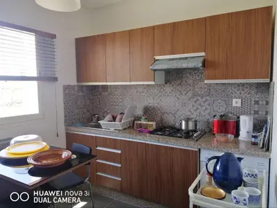 a kitchen with wooden cabinets and a counter top at Appartement Résidence balnéaire Dar Al bahr in Sidi Rahal
