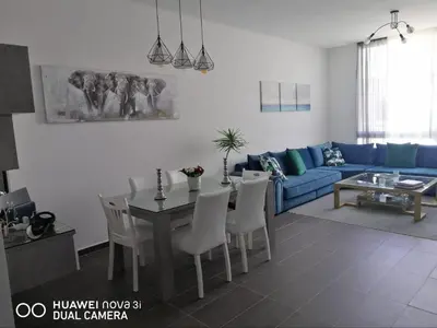 a living room with a blue couch and a table and chairs at Appartement Résidence balnéaire Dar Al bahr in Sidi Rahal