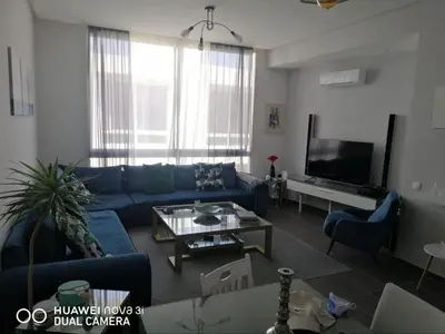 a living room with a blue couch and a tv at Appartement Résidence balnéaire Dar Al bahr in Sidi Rahal