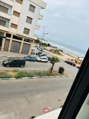 a parking lot with cars parked next to the beach at Appartement vu sur mer in Pont Blondin