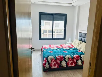 a bedroom with a bed with a floral comforter and a window at Appartement vu sur mer in Pont Blondin