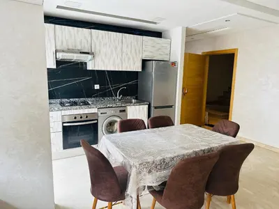 a kitchen with a table with chairs and a stove at Appartement vu sur mer in Pont Blondin