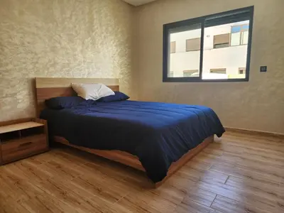 a bedroom with a bed with a blue comforter and a window at Bab fes Appartement 2 pièces à Aïn Sebaâ Casablanca in Aïn Sebaa