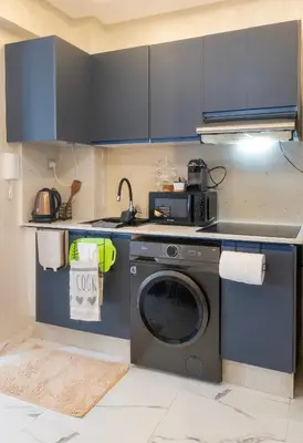 a kitchen with a washing machine and blue cabinets at Charmant et cosy appartement en plein centre ville in Casablanca