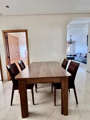 a wooden dining room table with chairs and a mirror at Wifak beach rental in Temara