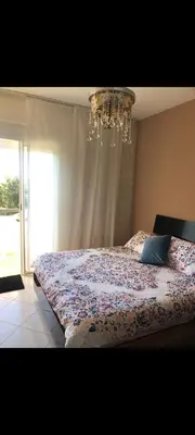 a bedroom with a large bed with a chandelier at Bahia golf beach pavillon in Bouznika