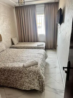 a hotel room with two beds and a television at Elégant appartement 2 Bedroom près de la plage Rabat in Rabat