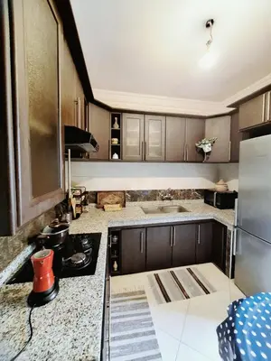 a kitchen with wooden cabinets and a counter top at Apartment with sea view in El Harhoura