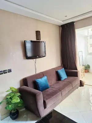 a living room with a brown couch and a flat screen tv at Apartment with sea view in El Harhoura
