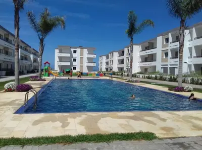 a large swimming pool with palm trees and buildings at Seaside apartment in El Mansouria in Mansouria
