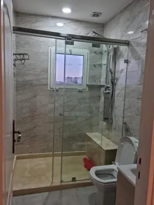a bathroom with a shower with a toilet and a window at Appartement de luxe avec piscine à Mansouria in Mansouria
