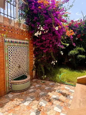 a garden with a fence and purple flowers at Villa Rina in Sidi Rahal
